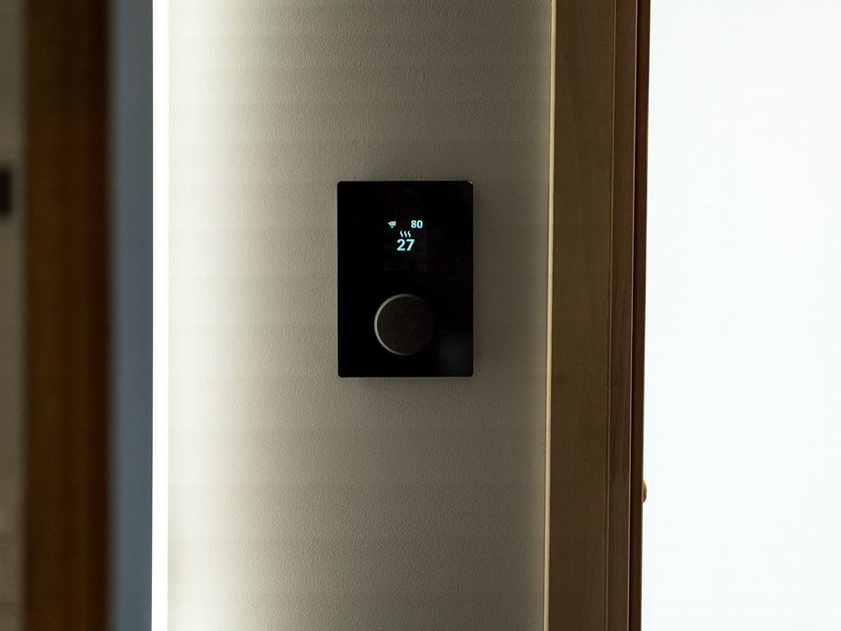 Modern black smart thermostat mounted on a wall