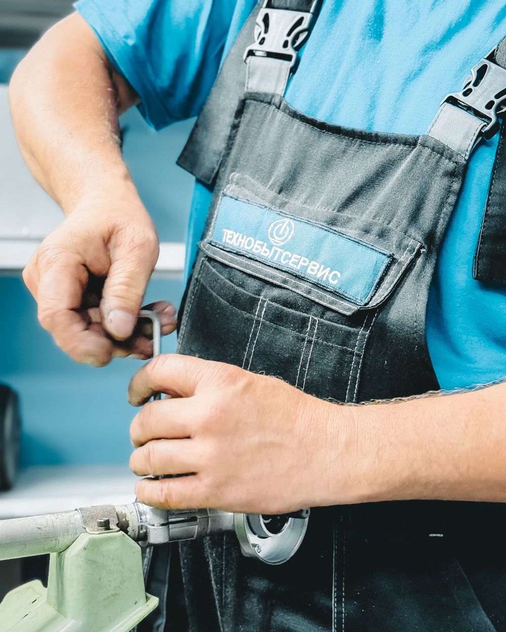 Plumber in work overalls repairing a pipe with a wrench