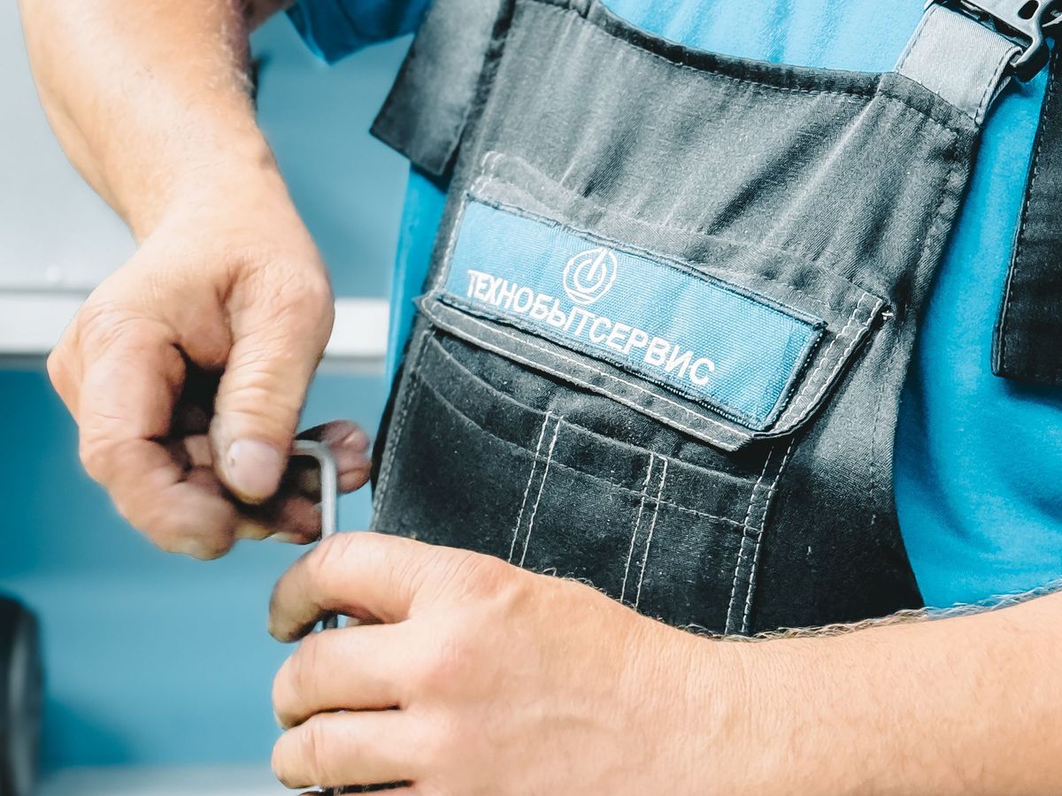 Plumber in blue uniform tightening a pipe with a wrench