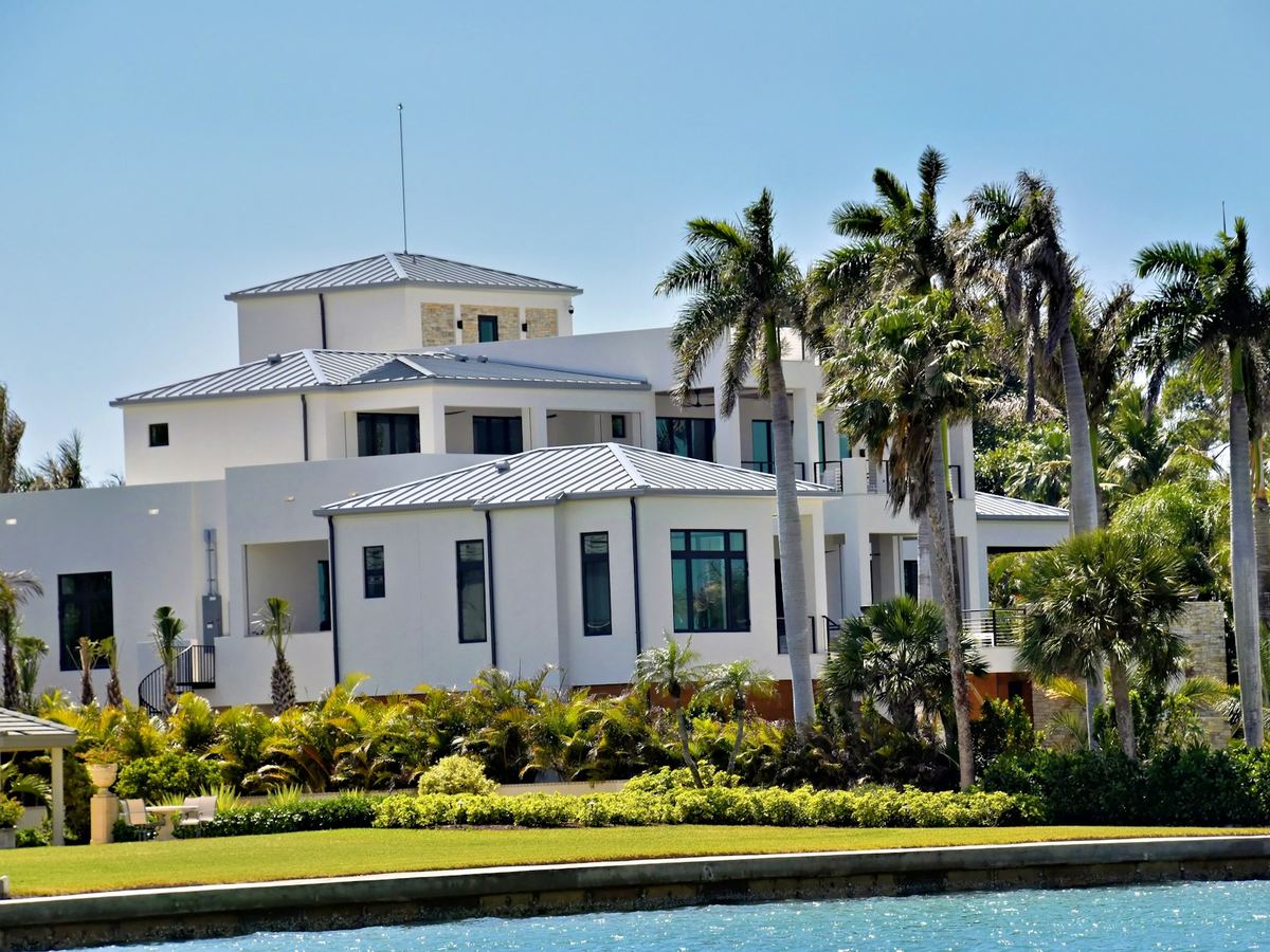Large white Florida home with palm trees and a finished roof