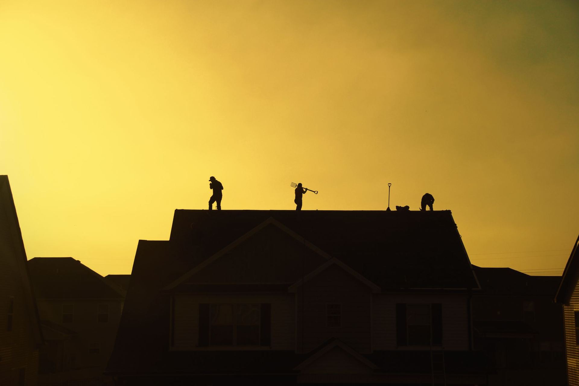 Roofing crew silhouetted on a rooftop at sunset
