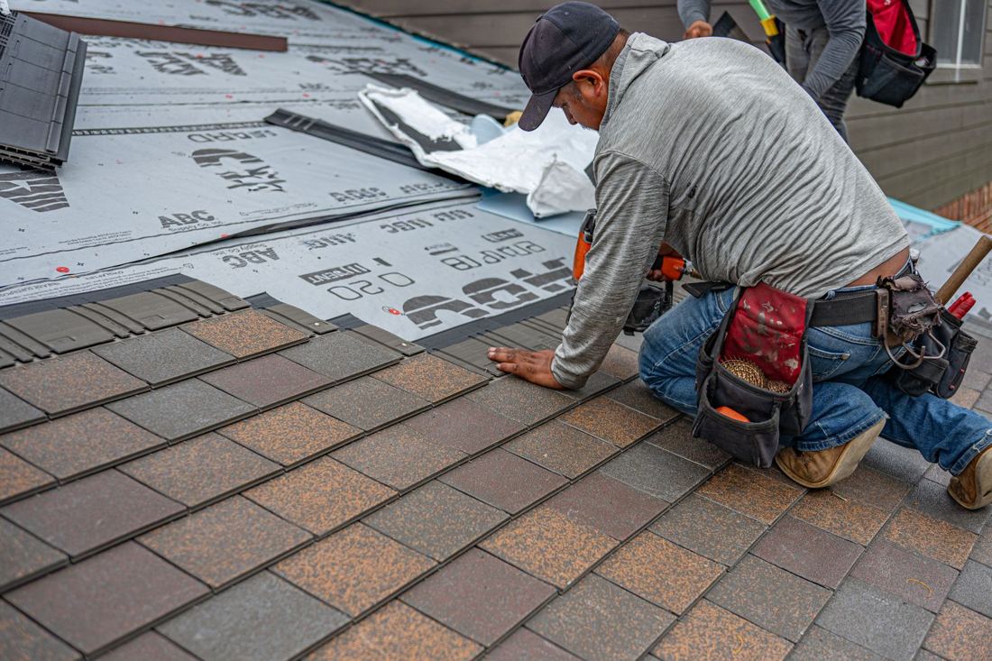 Roofer installing asphalt shingles on a home roof